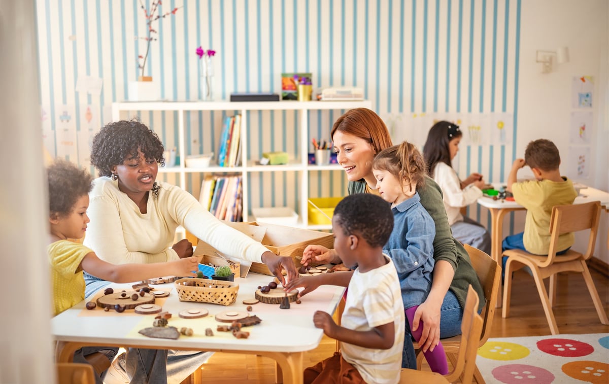 Profesora guiando a un grupo diverso de niños en actividad de materiales naturales