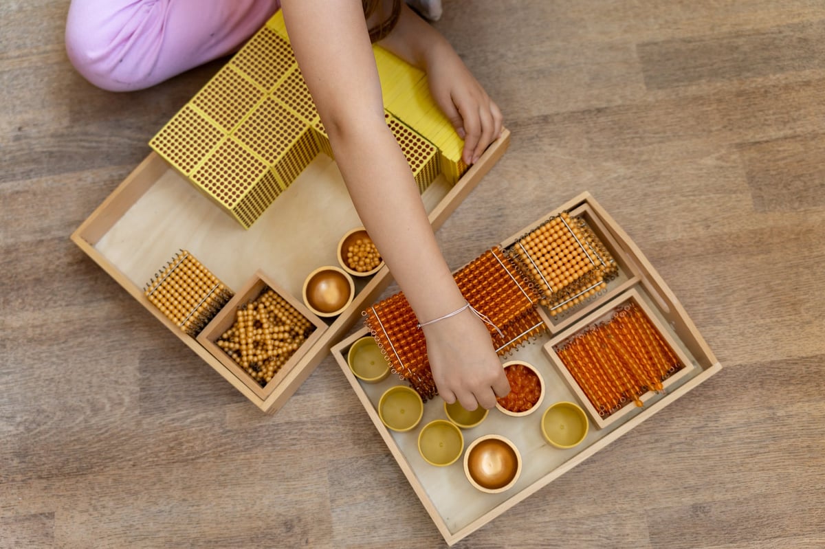 Niño contando con el material dorado Montessori para aprender matemáticas y el sistema decimal