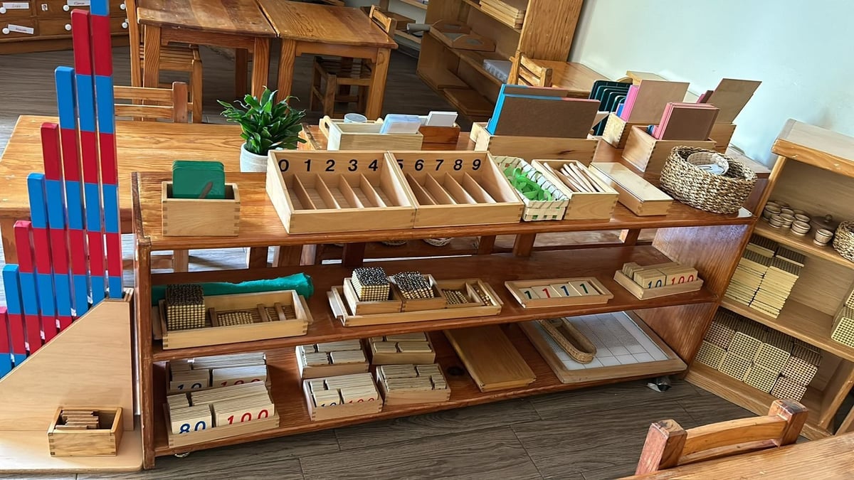 Wooden Montessori classroom shelving unit with organized educational materials, boxes, and learning supplies arranged by subject